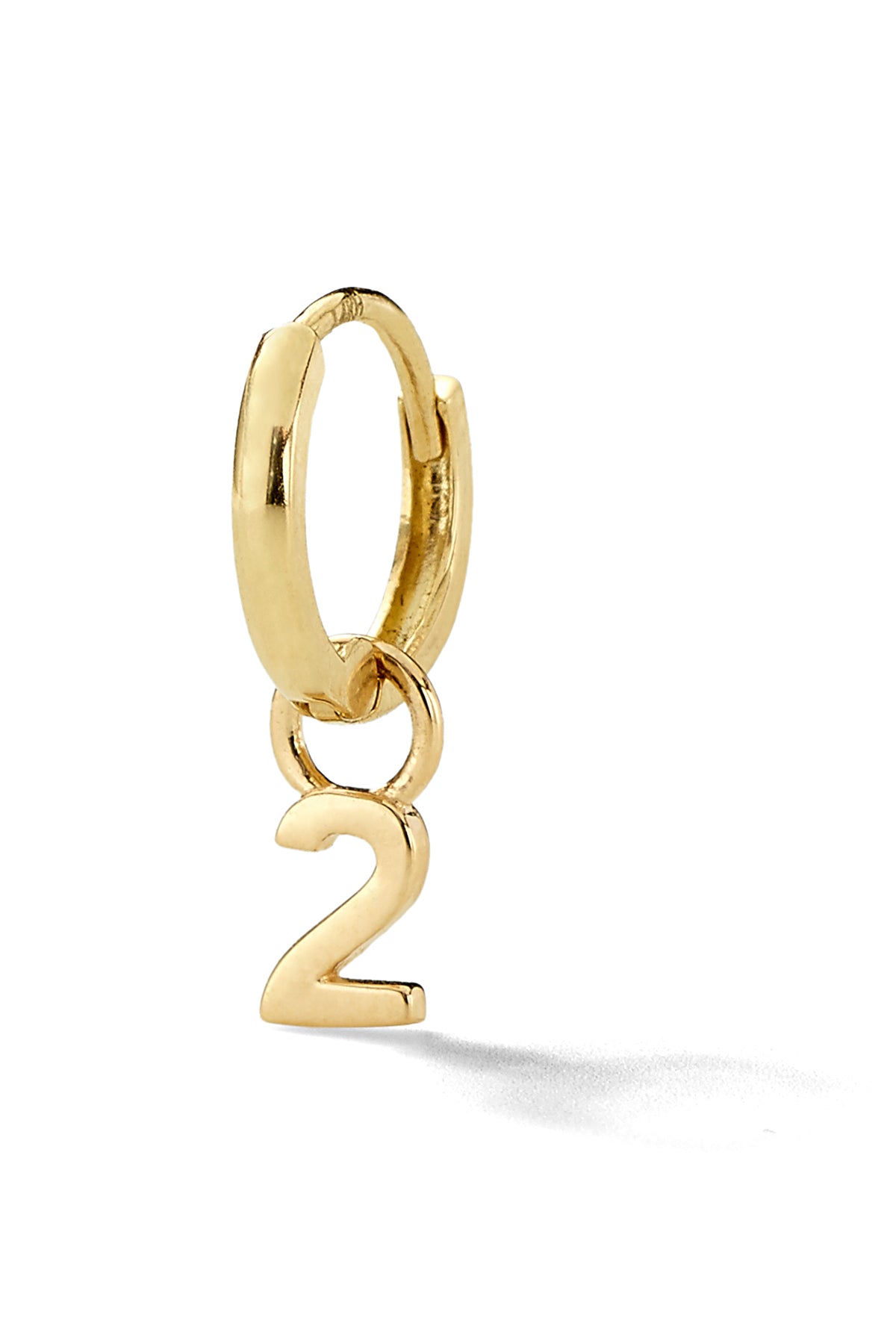 Gold number "2" huggie hoop earring aginst a white background