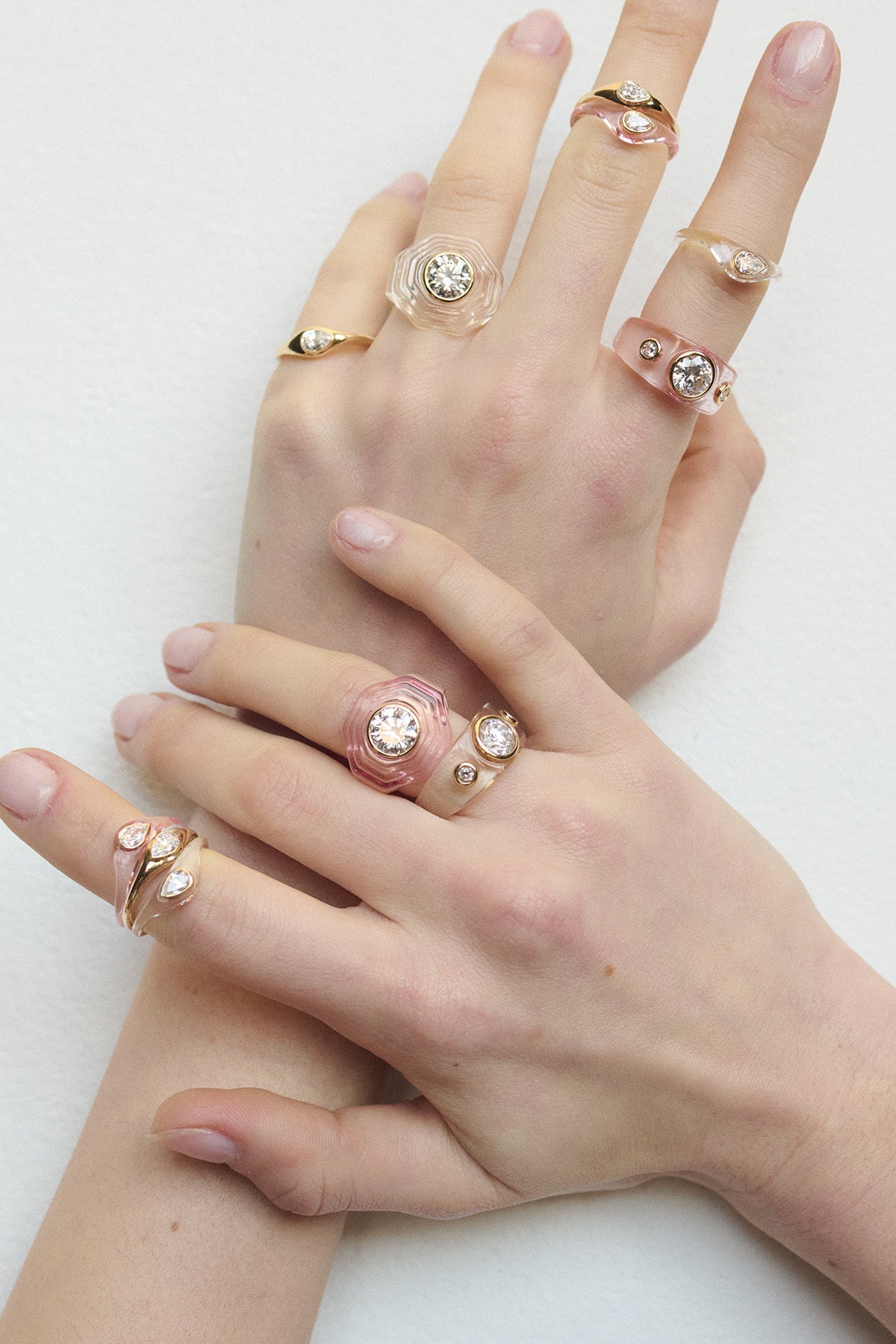 Model wearing multiple rings on both hands laying against a white background