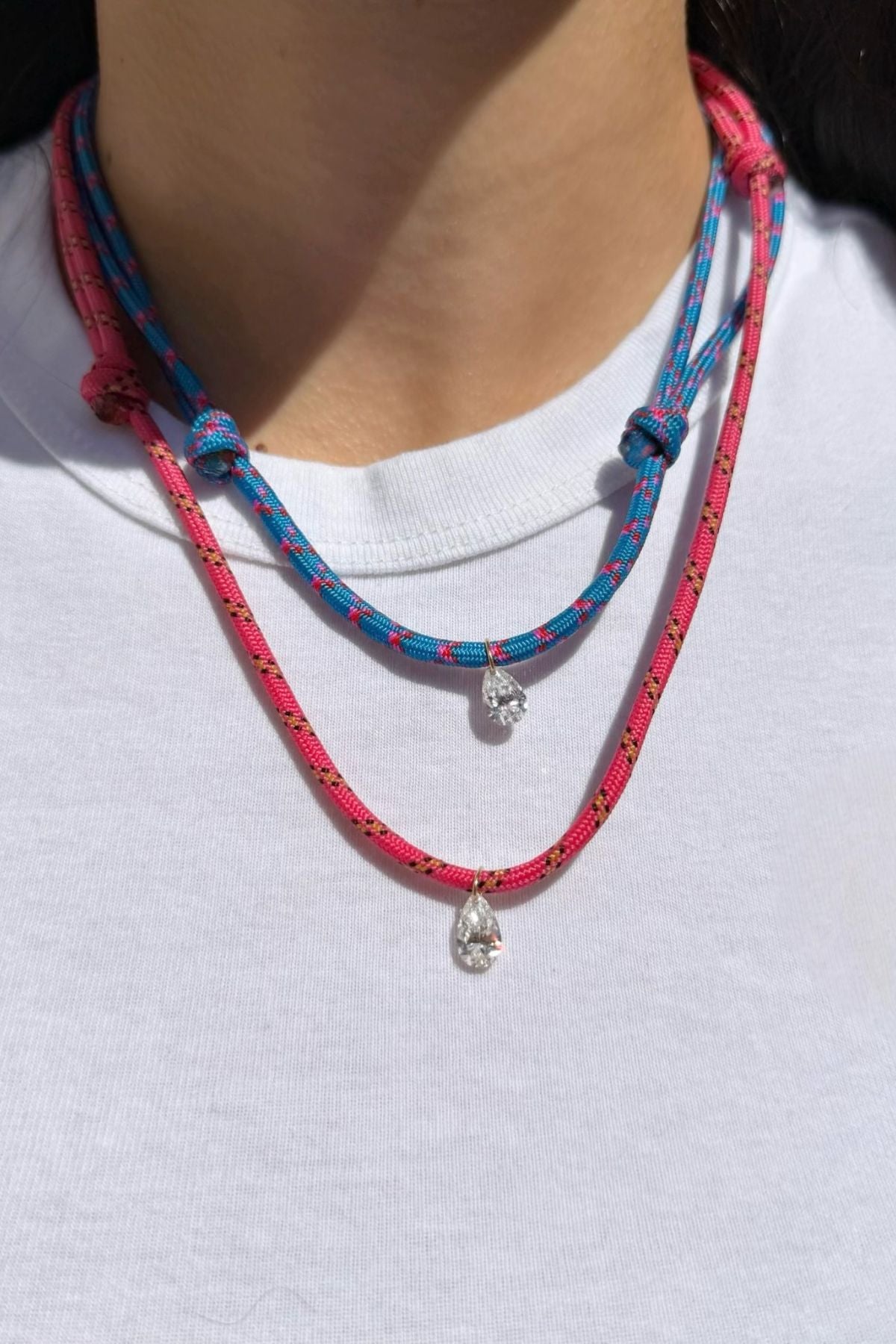 Model wearing a blue and pink paracord necklace with a white diamond charm on a white background