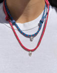 Model wearing a blue and pink paracord necklace with a white diamond charm on a white background
