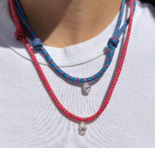 Model wearing a blue and a pink paracord necklace with a white diamond charm against a white background