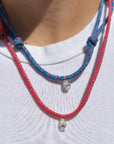 Model wearing a blue and a pink paracord necklace with a white diamond charm against a white background